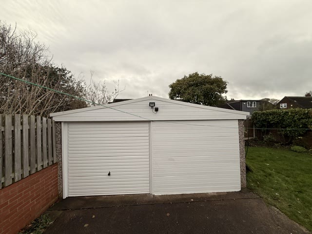 The same double garage with two white up-and-over doors and new white cladding