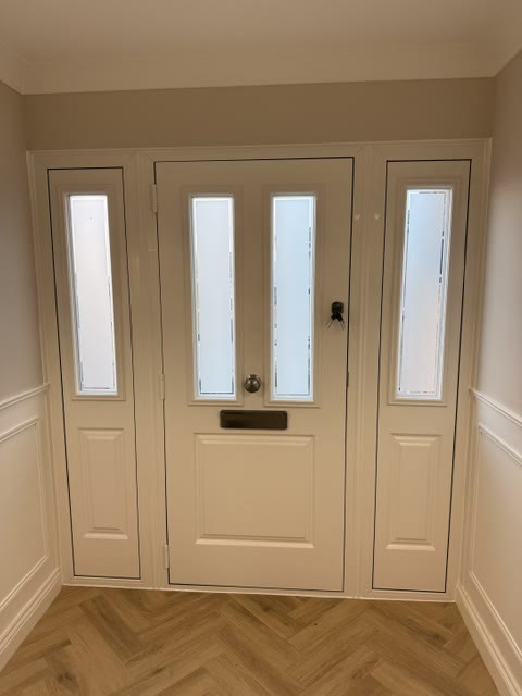 Cream composite front door with glazed side panels, photographed from the hallway