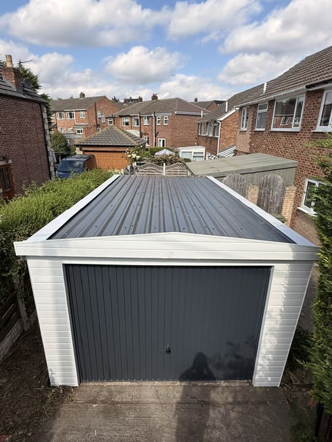 The same garage with a new box-profile roof, anthracite door and white cladding