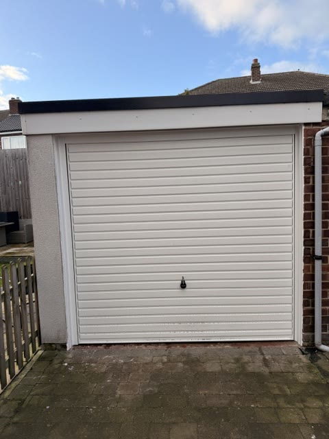 Cream insulated roller garage door between a rendered wall and brickwork