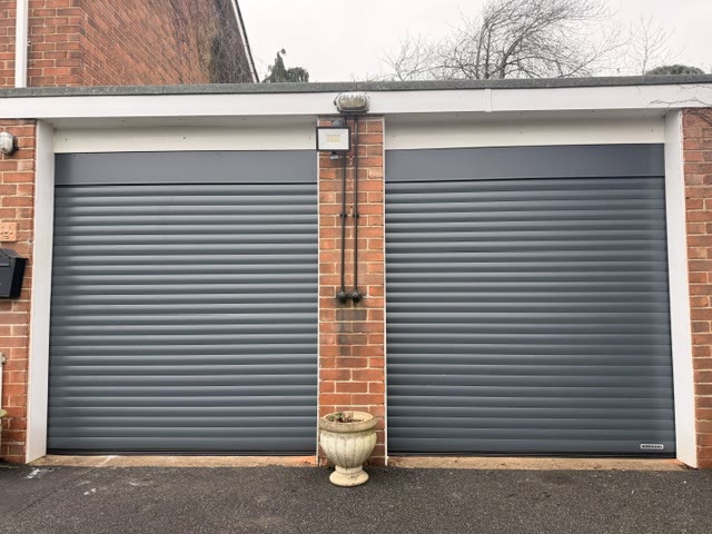 Two grey insulated roller doors fitted side by side on a garage block