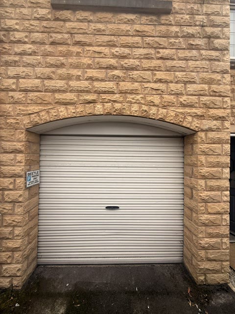 White roller door in an arched stone garage opening
