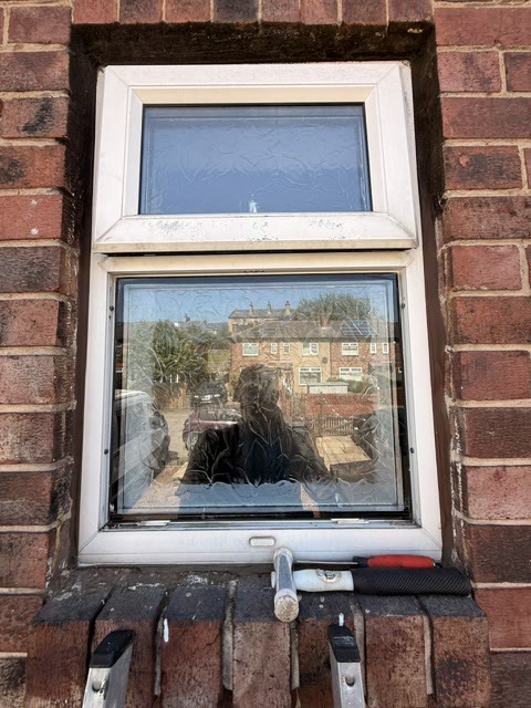 Misted double-glazed window in a discoloured white frame